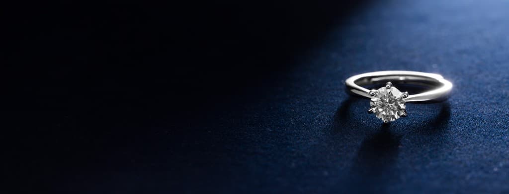 Diamond solitaire ring on navy velvet